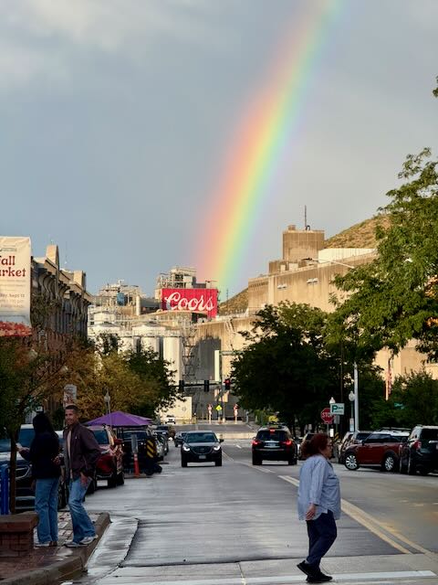 A rainbow arcs down over the Coors sign at the foot of the foothills in downtown Golden, Colorado